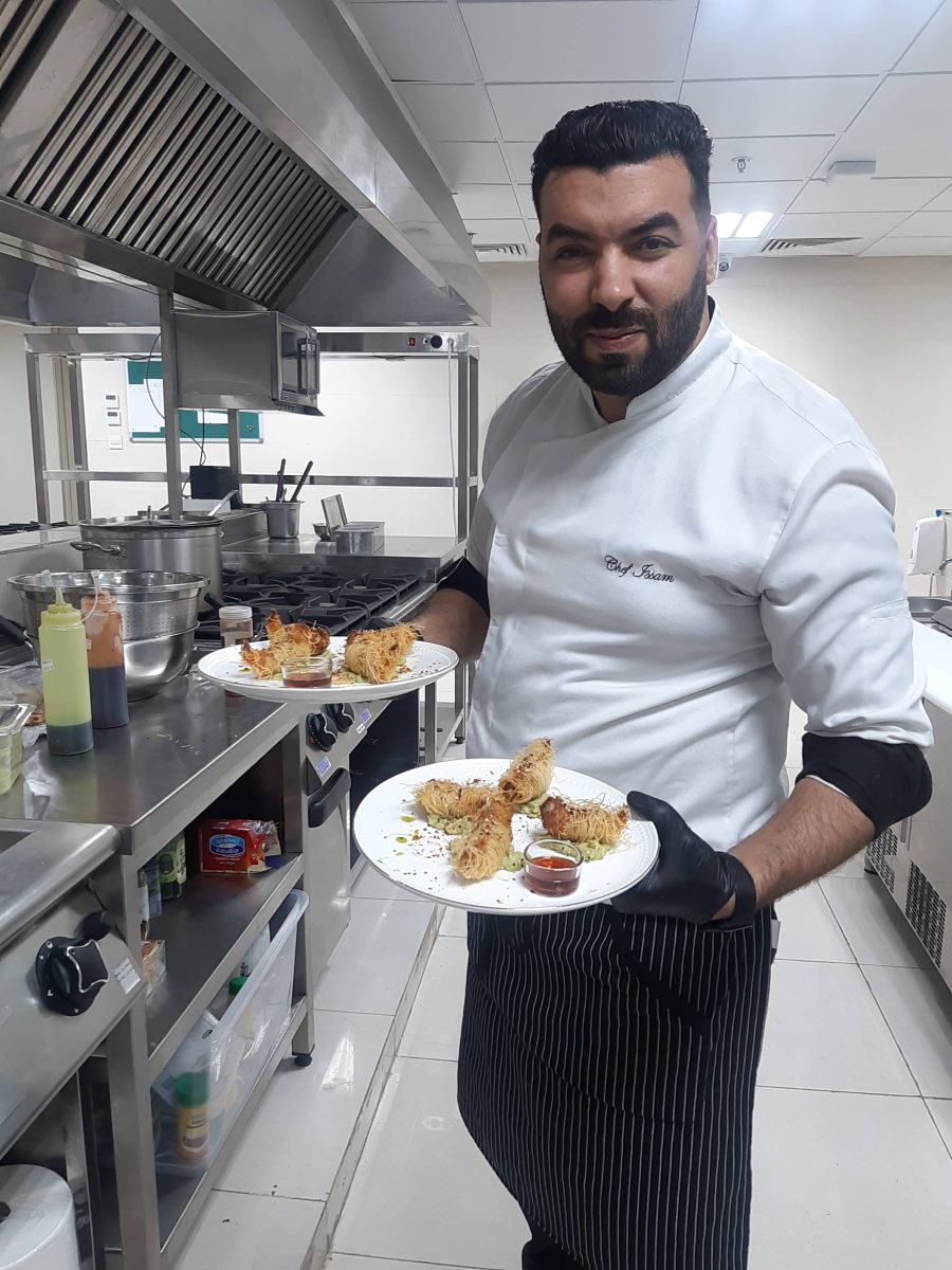 Cuisinier présentant deux assiettes dressées en cuisine pro