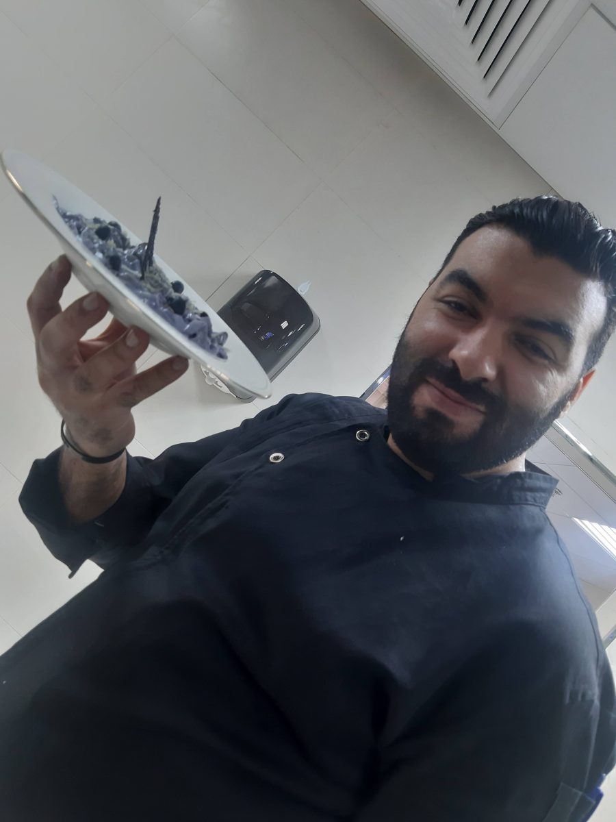 Cuisinier présentant une assiette dressée en cuisine professionnelle