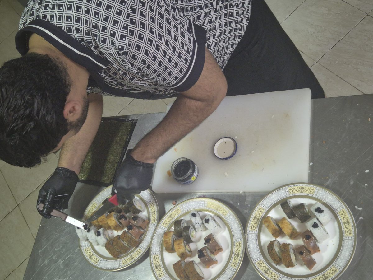 Cuisinier dressant des makis sur des assiettes à liseré doré