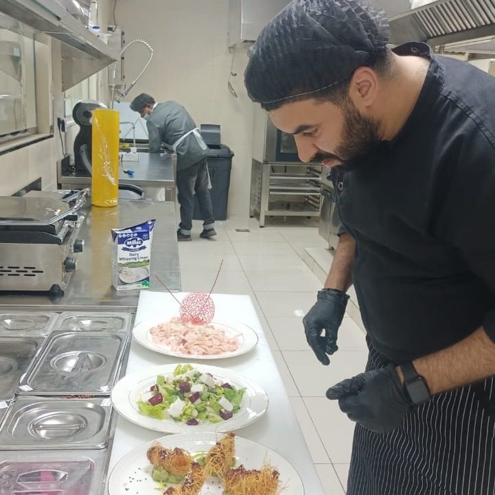 Cuisinier dressant des assiettes sur un plan de travail