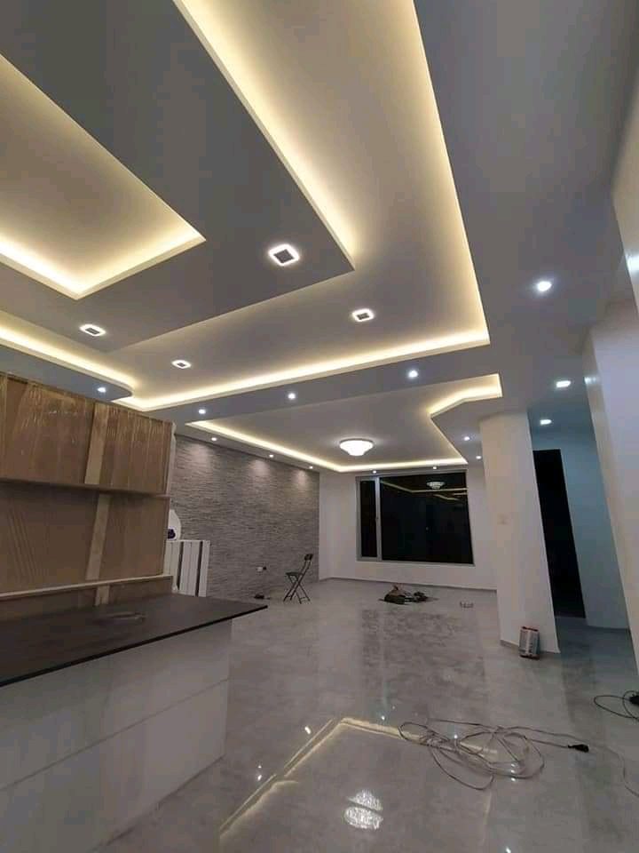 Grand faux plafond en plâtre à décrochés et gorges LED dans un séjour