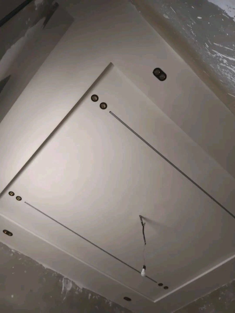 Faux plafond blanc à cadre en gradins et lignes LED en biais