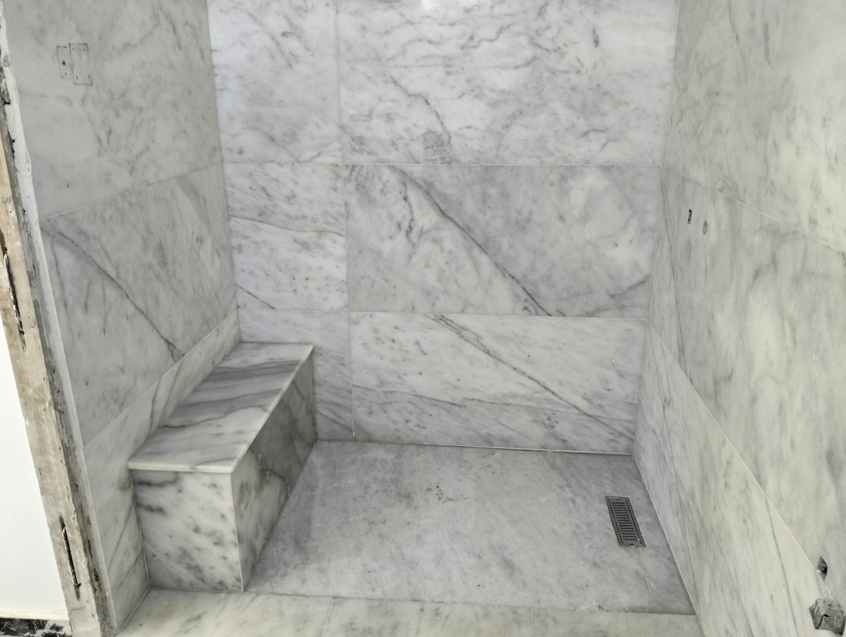 Cabine de hammam habillée de marbre blanc veiné avec banquette