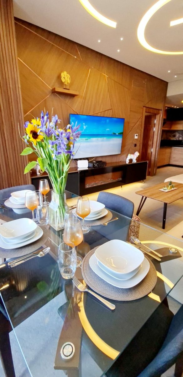 Salle à manger dressée devant un séjour à meuble TV rétro-éclairé