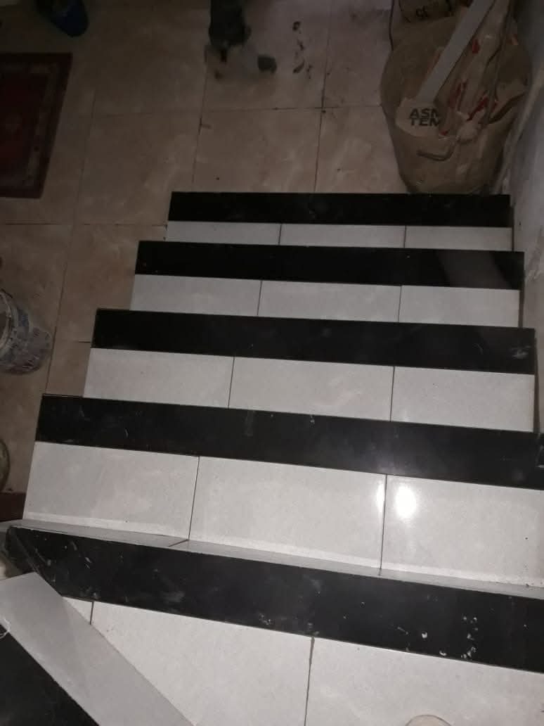 Escalier en cours de carrelage à marches claires et nez noir