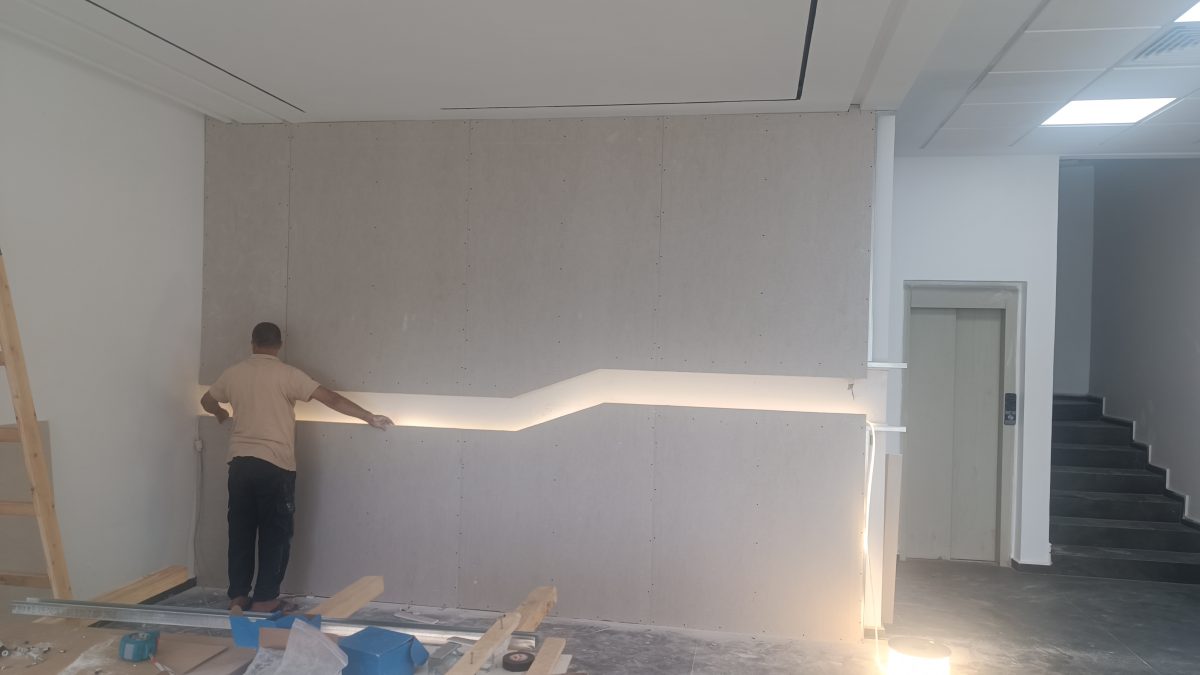 Habillage mural MDF à bande LED zigzag dans un hall, en cours