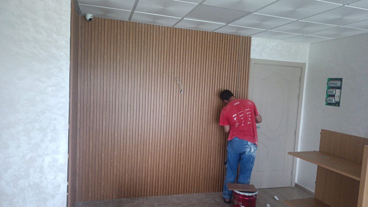 Mur en tasseaux de bois verticaux avec caméra, finitions en cours