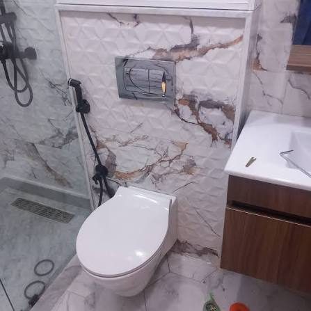 WC suspendu avec plaque de commande dans une salle de bain effet marbre