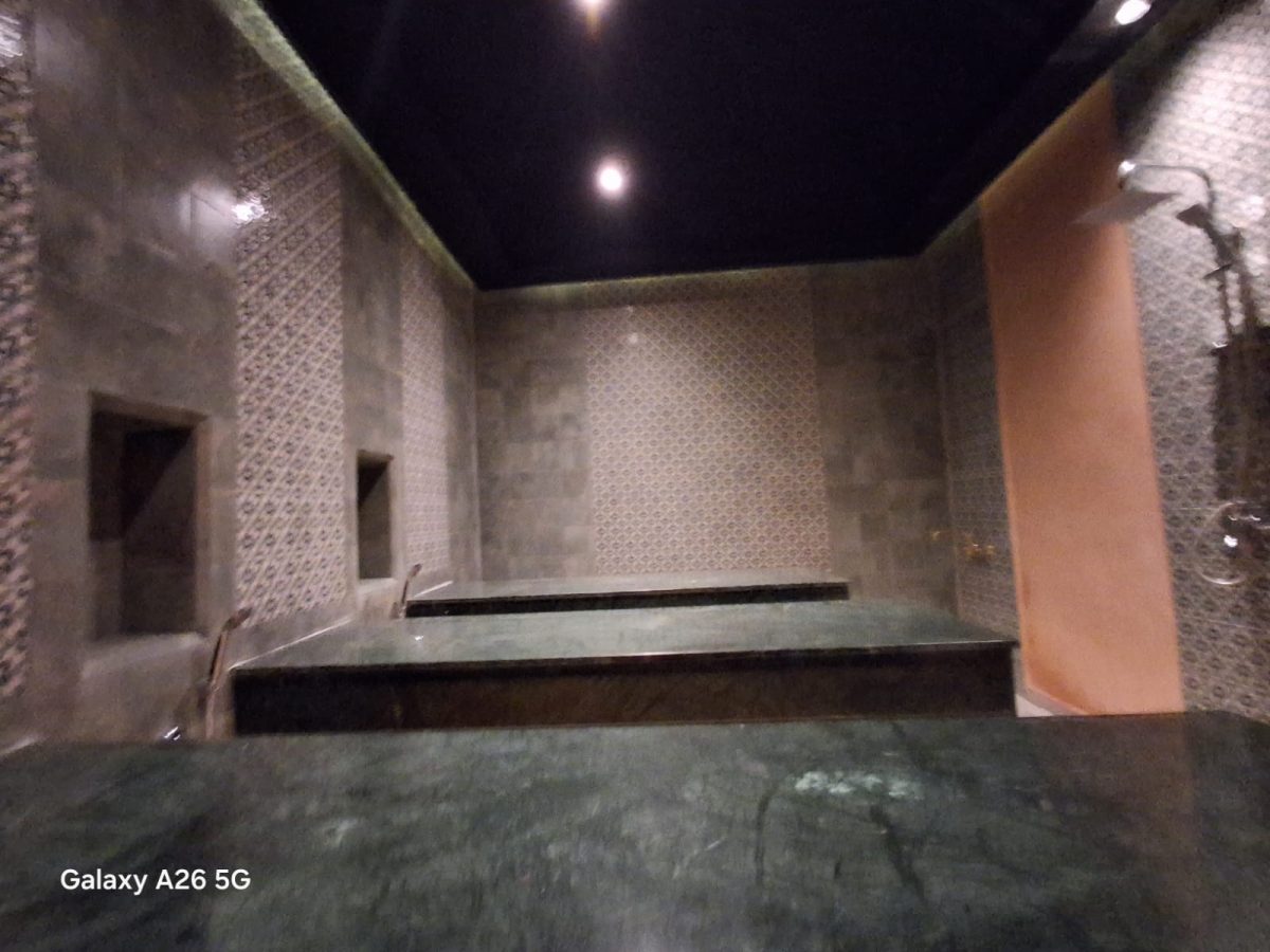 Hammam à banquettes en marbre vert et murs en zellige
