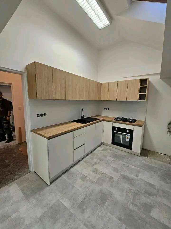 Cuisine en L à façades blanches et bois clair avec plan effet bois