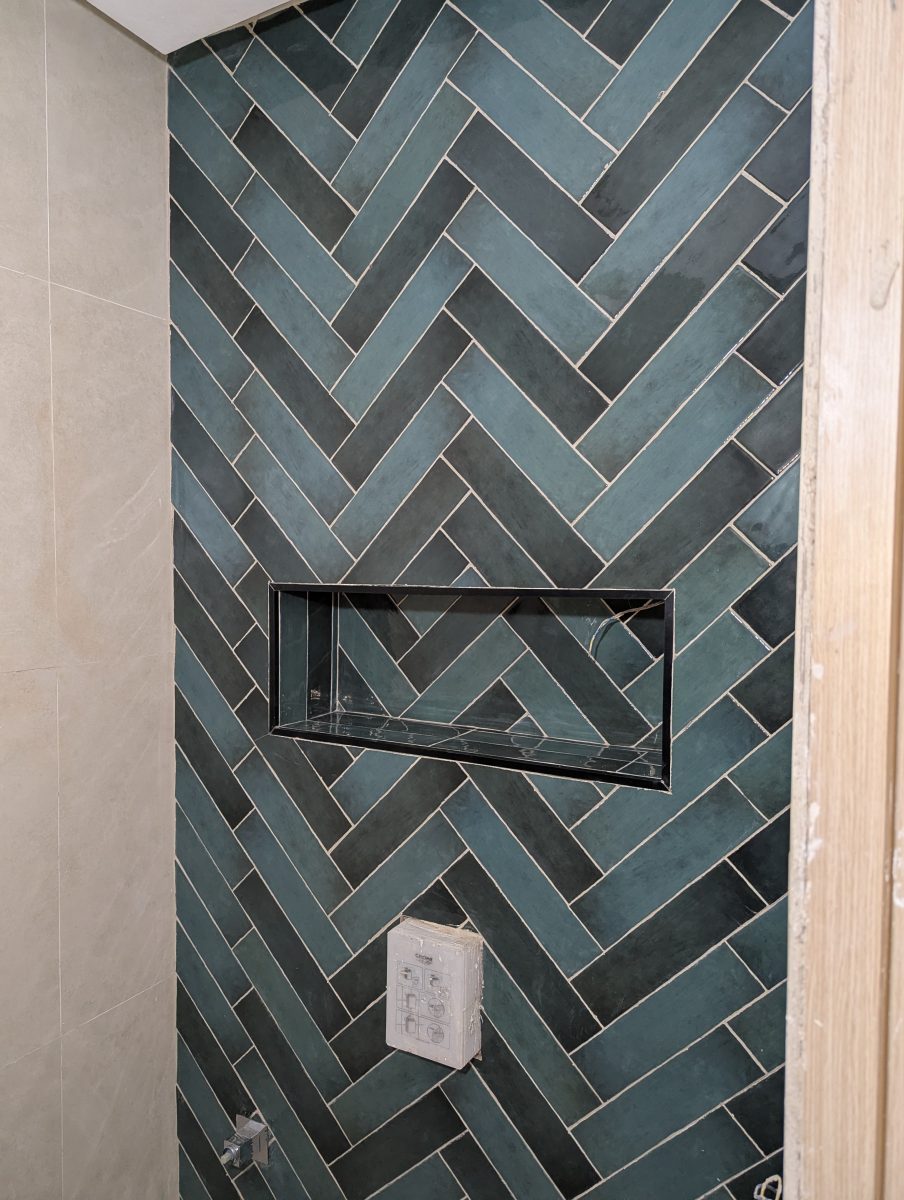 Douche carrelée en faïence vert-de-gris en chevrons avec niche inox