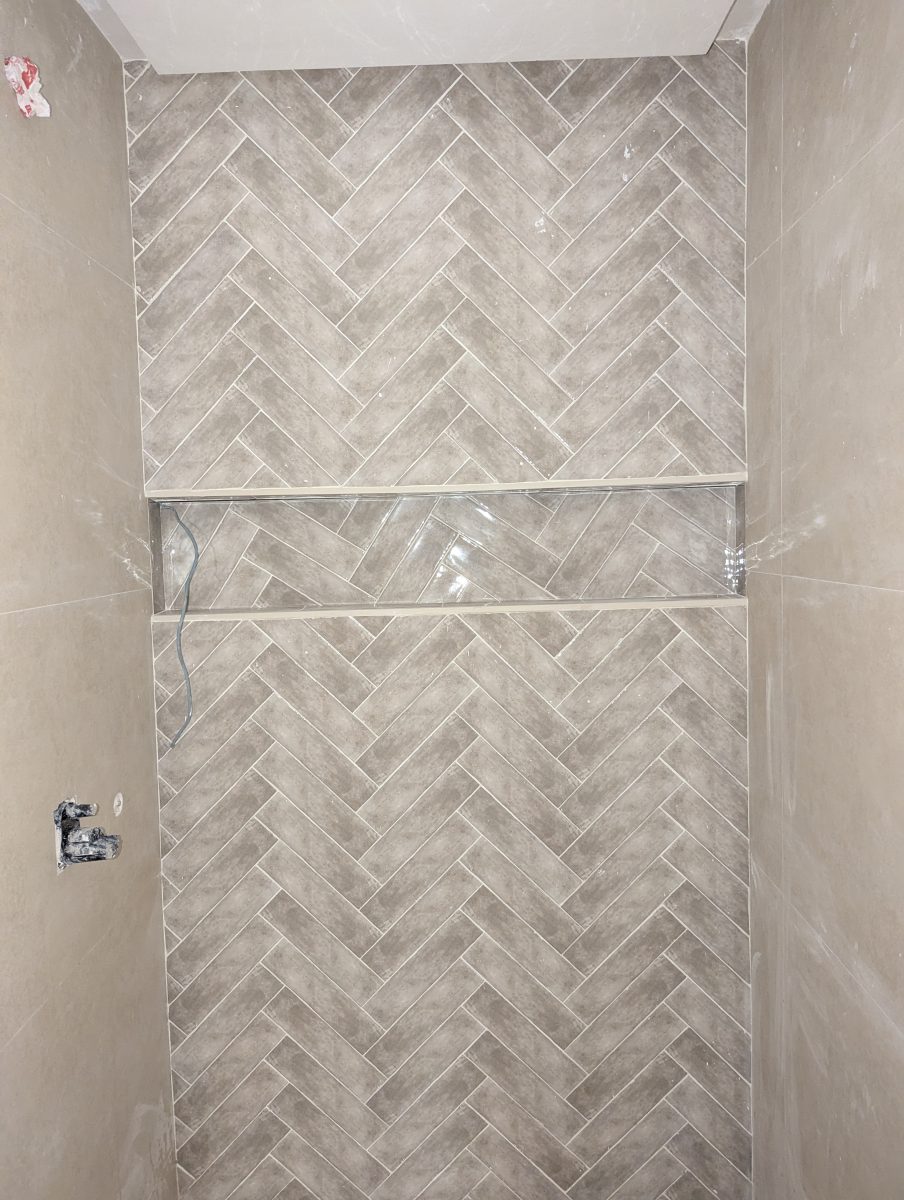 Douche carrelée effet béton en chevrons avec niche à listel inox