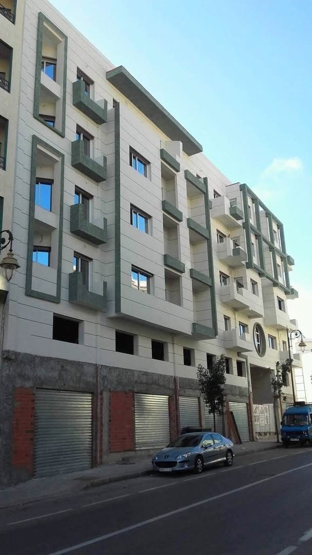 Immeuble d'angle à façade enduite et encadrements en pierre verte