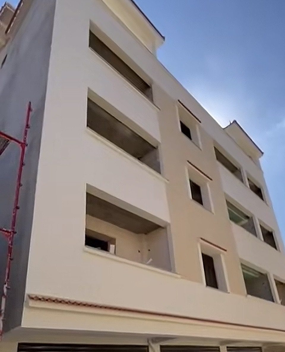 Immeuble à façade enduite beige et crème à bandeaux