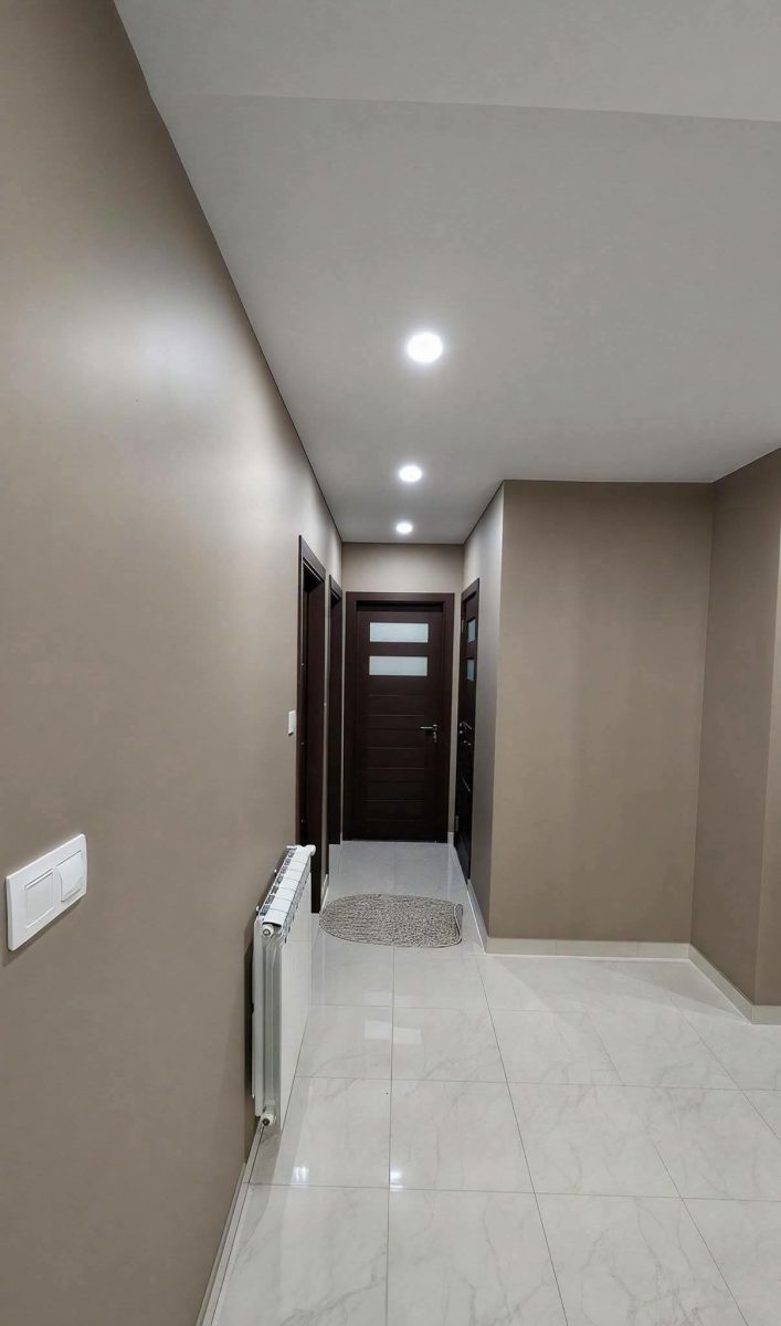 Couloir peint taupe avec portes en bois foncé et sol en marbre