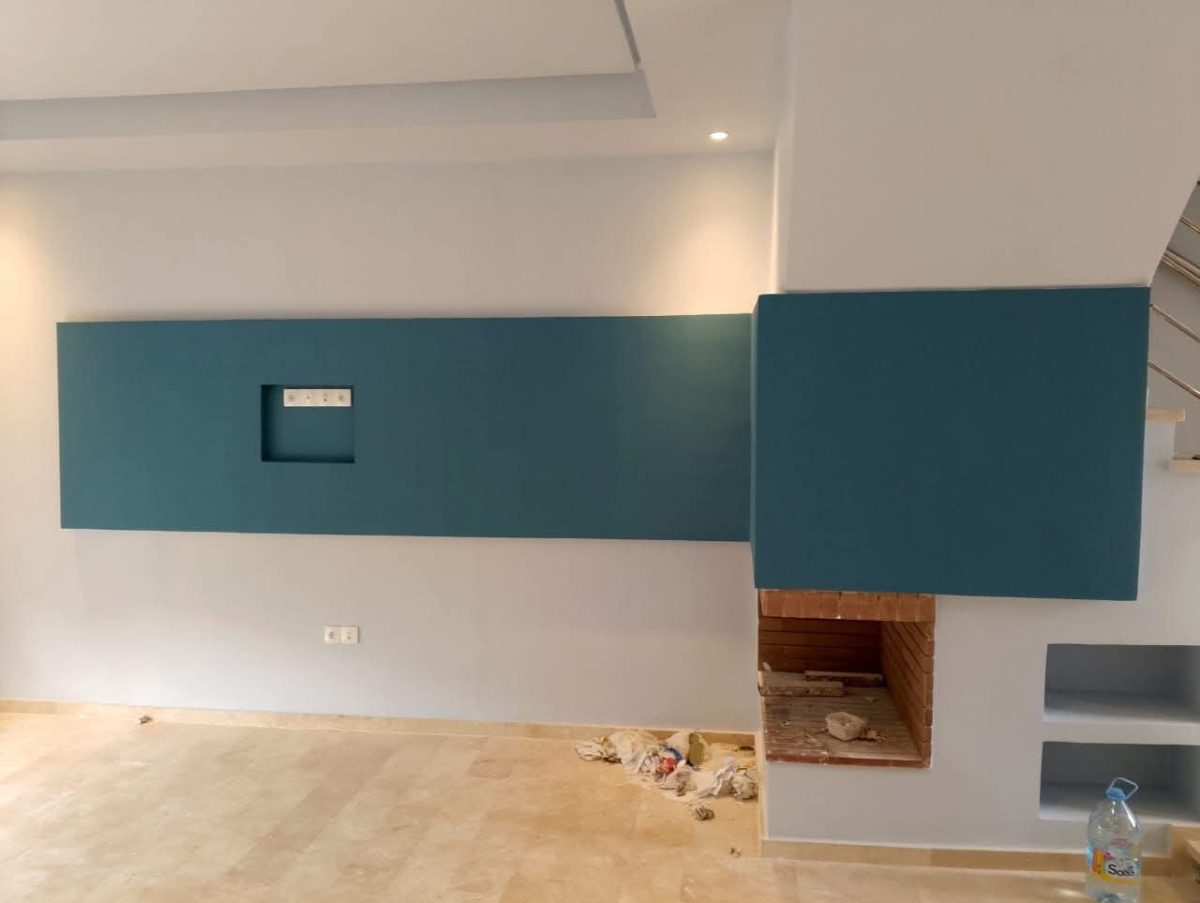 Séjour à bandeau mural bleu canard autour d'une cheminée
