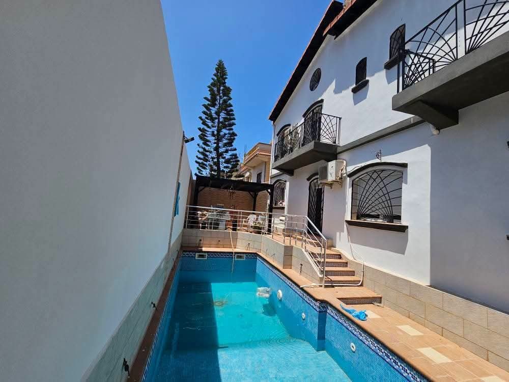 Extérieur d'une villa blanche avec piscine et escalier inox
