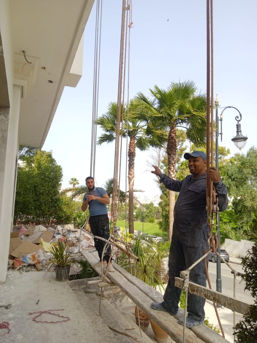 Ouvriers sur une plateforme suspendue devant une façade en rénovation