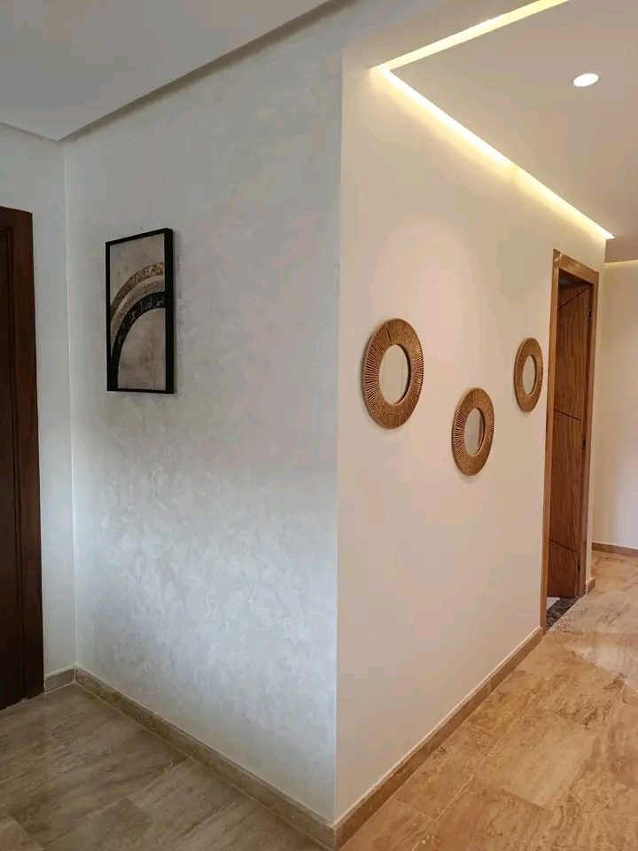 Couloir à enduit nacré blanc et miroirs ronds en rotin