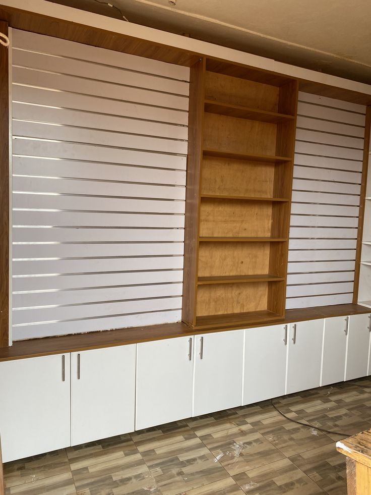 Bibliothèque murale à lattes blanches et niches en bois clair, en cours