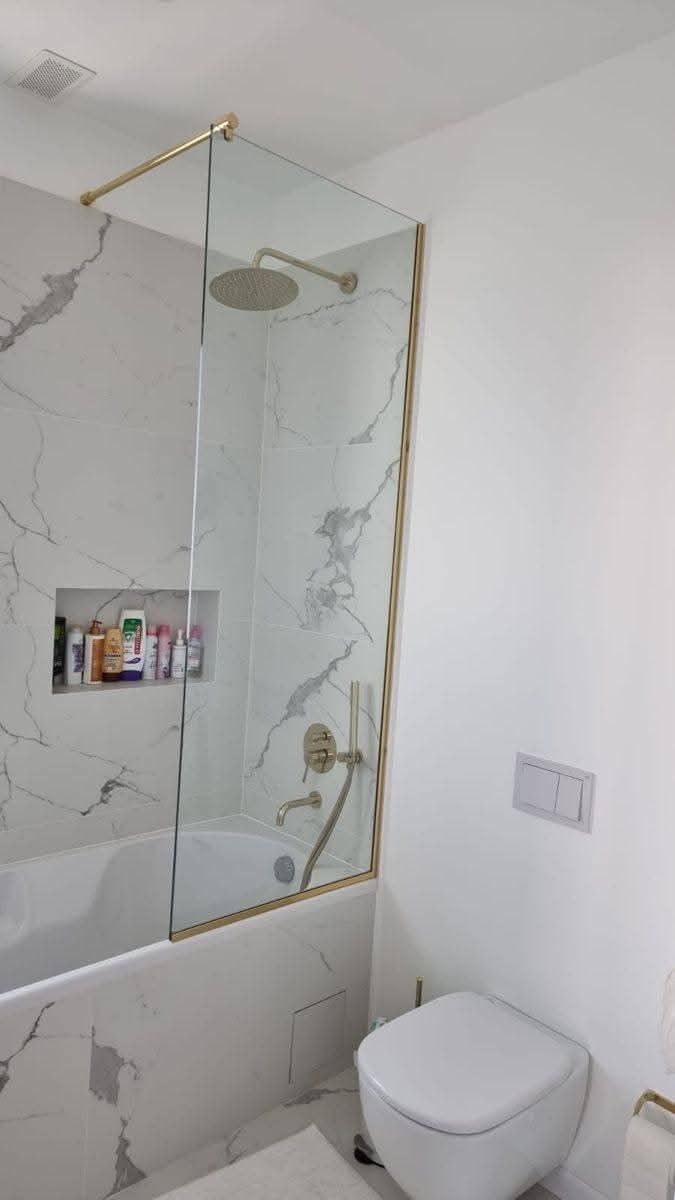 Pare-baignoire en verre à cadre laiton doré dans une salle de bain