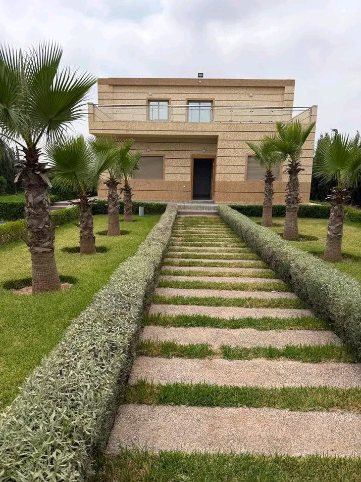 Villa avec allée de dalles engazonnées bordée de palmiers