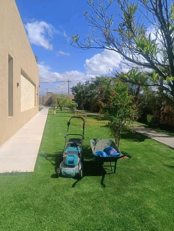 Jardin entretenu avec tondeuse et brouette le long d'une villa