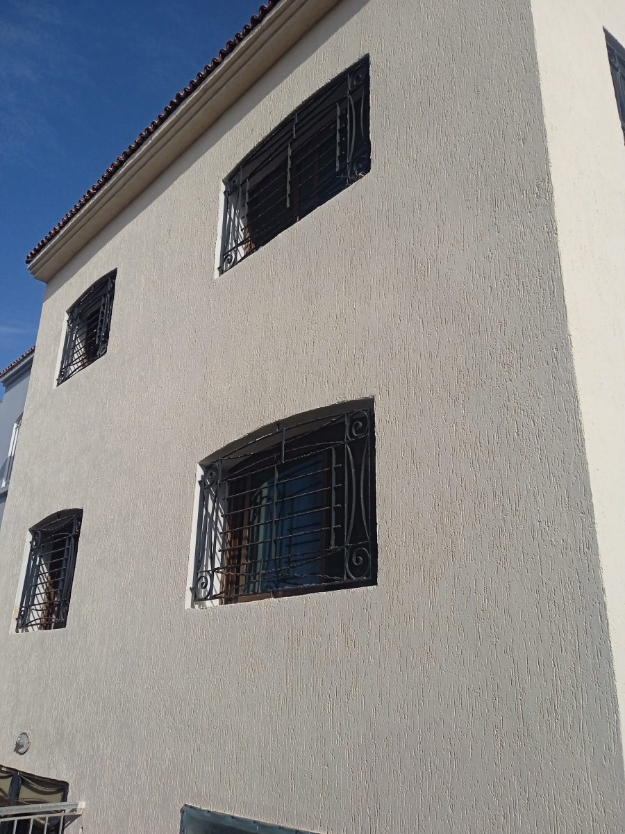 Façade ravalée en enduit taloché beige à grilles en fer forgé