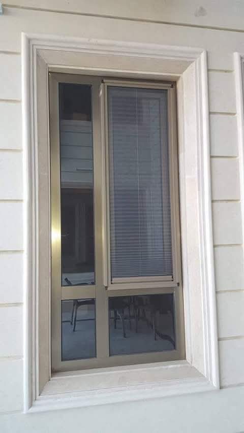 Fenêtre aluminium bronze à store intégré et chambranle en pierre