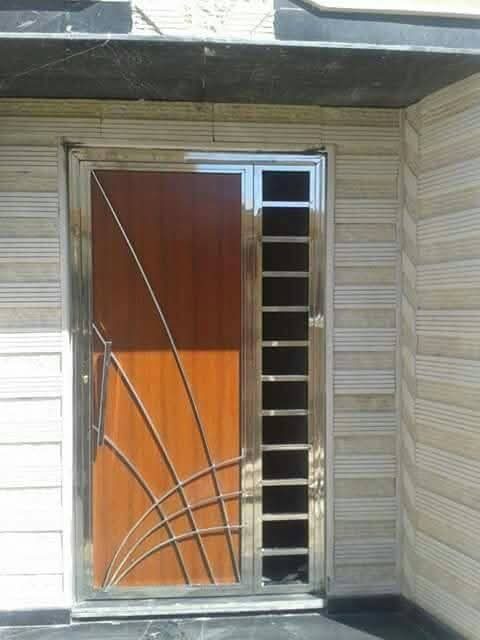 Porte d'entrée à grille inox à rayons sur parement pierre