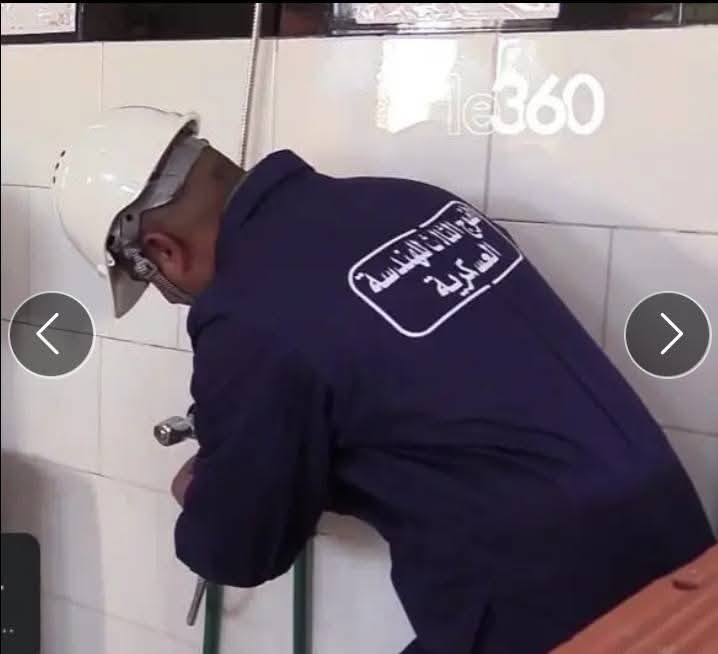 Technicien réparant une plomberie sur un mur carrelé