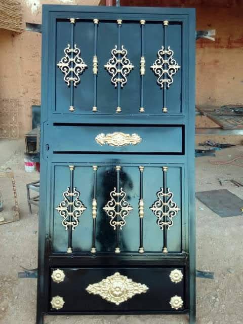 Grille de porte en fer forgé noir à fleurons dorés, en atelier