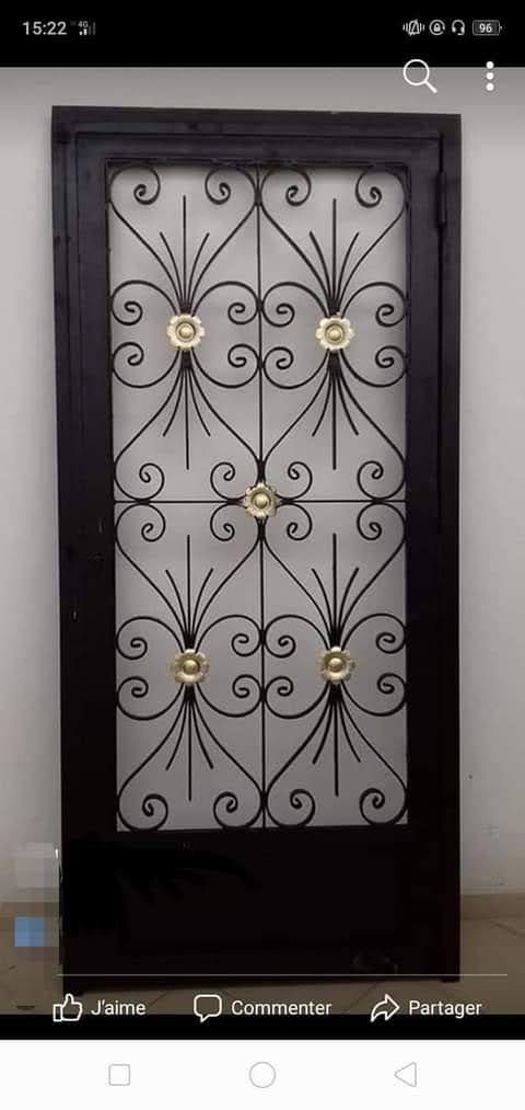 Grille de porte en fer forgé noir à volutes et fleurons dorés
