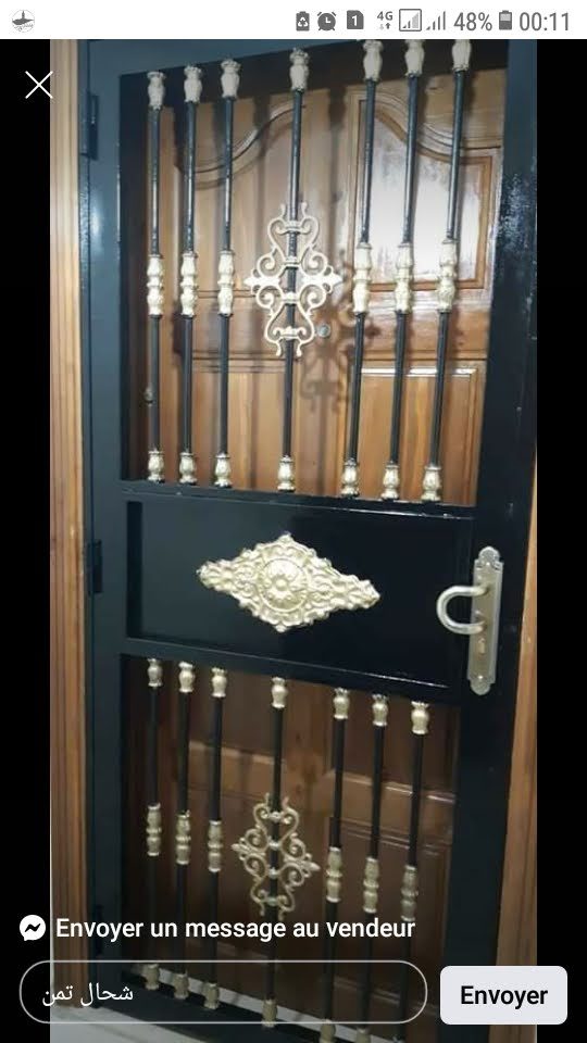 Grille de porte en fer forgé noir à volutes et fleurons dorés