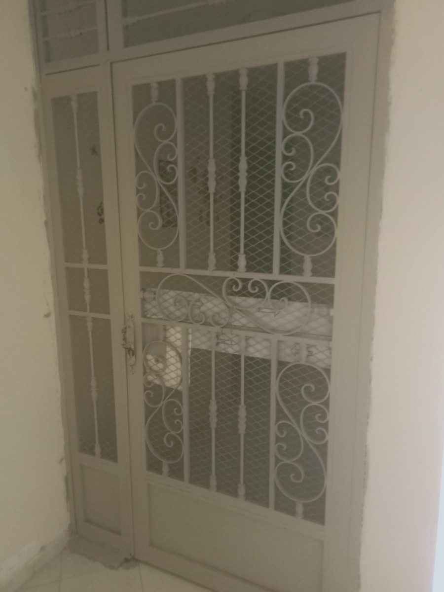 Grille de porte en fer forgé laqué blanc à volutes et grillage