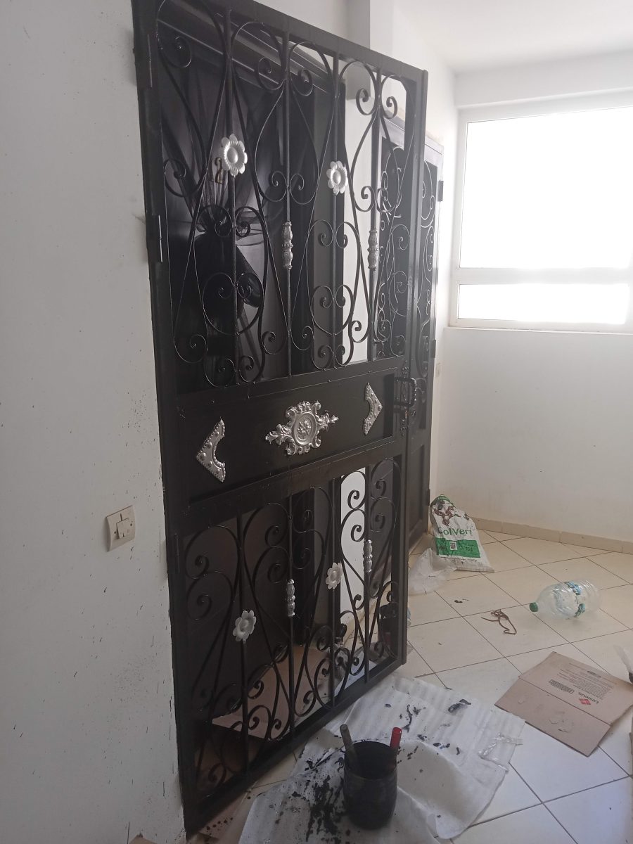 Grille de porte en fer forgé noir à volutes et fleurons argentés