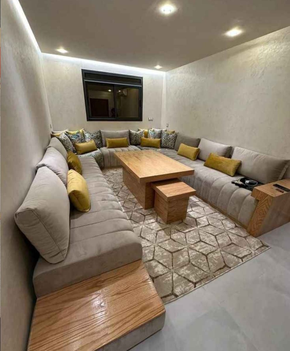 Salon marocain en U tapissé gris-taupe avec table basse en bois
