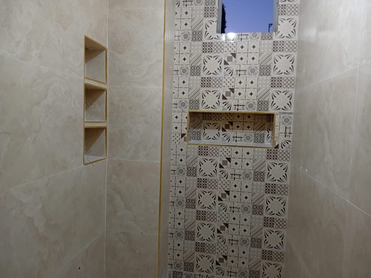 Douche en grès effet travertin beige à bande de carreaux à motifs