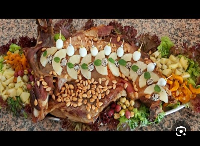 Méchoui garni de pommes de terre, olives et pignons
