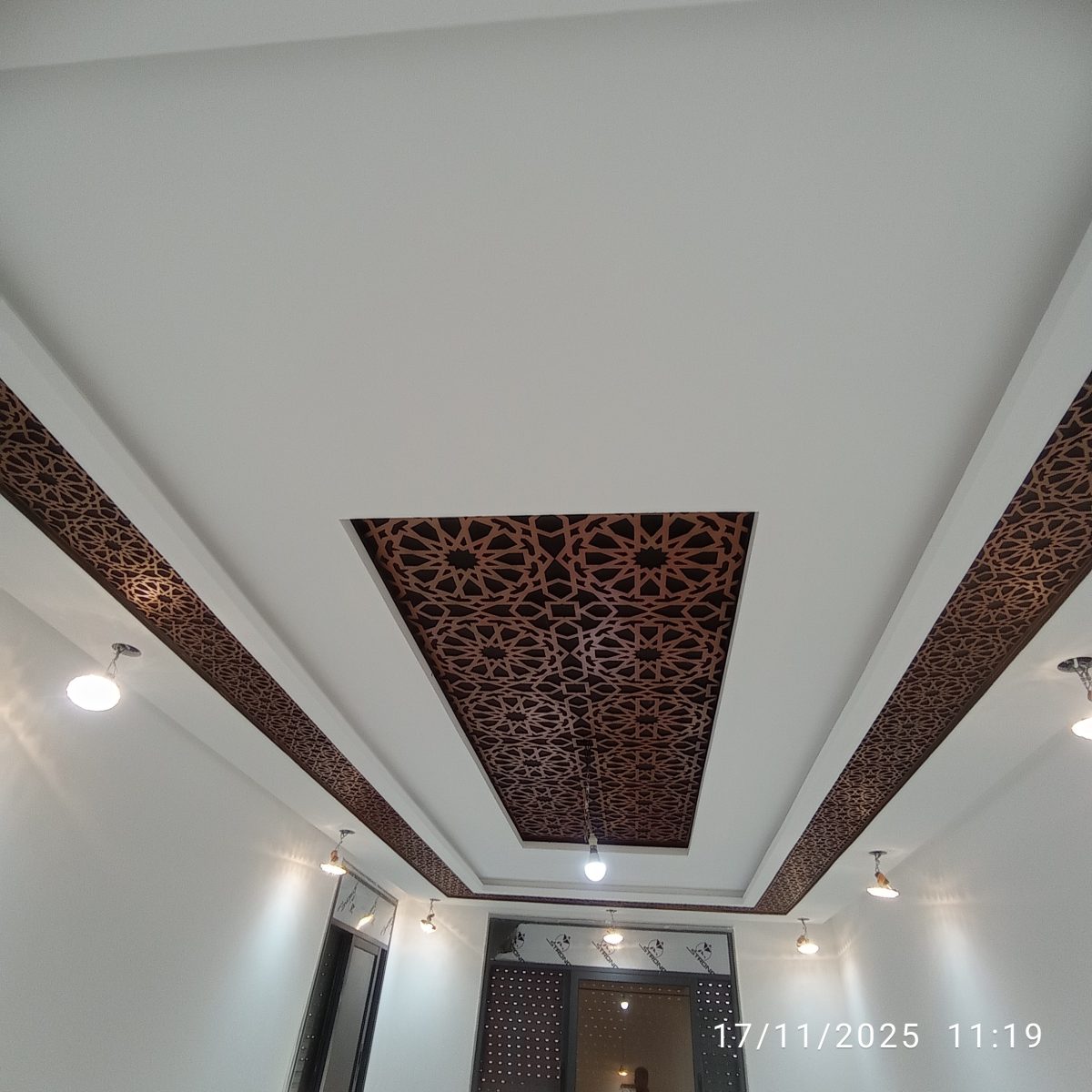 Faux plafond à panneau moucharabieh cuivré rétroéclairé dans un couloir