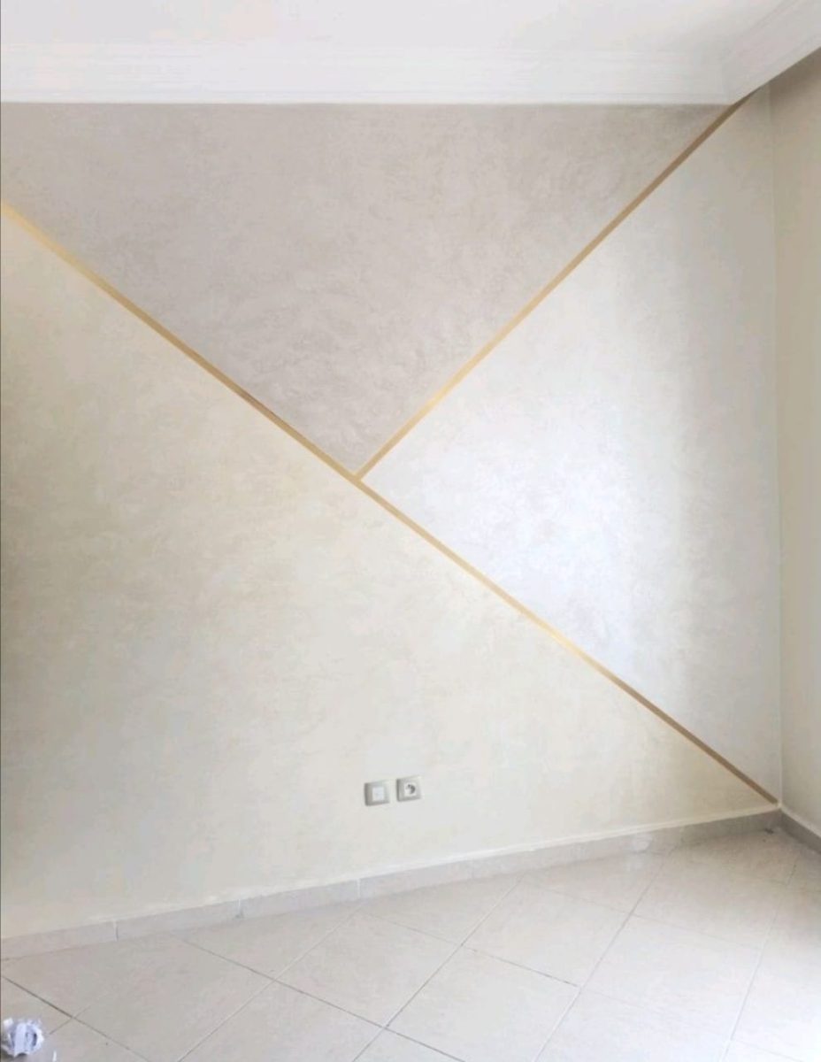 Mur en enduit décoratif nacré à motif géométrique et filets dorés