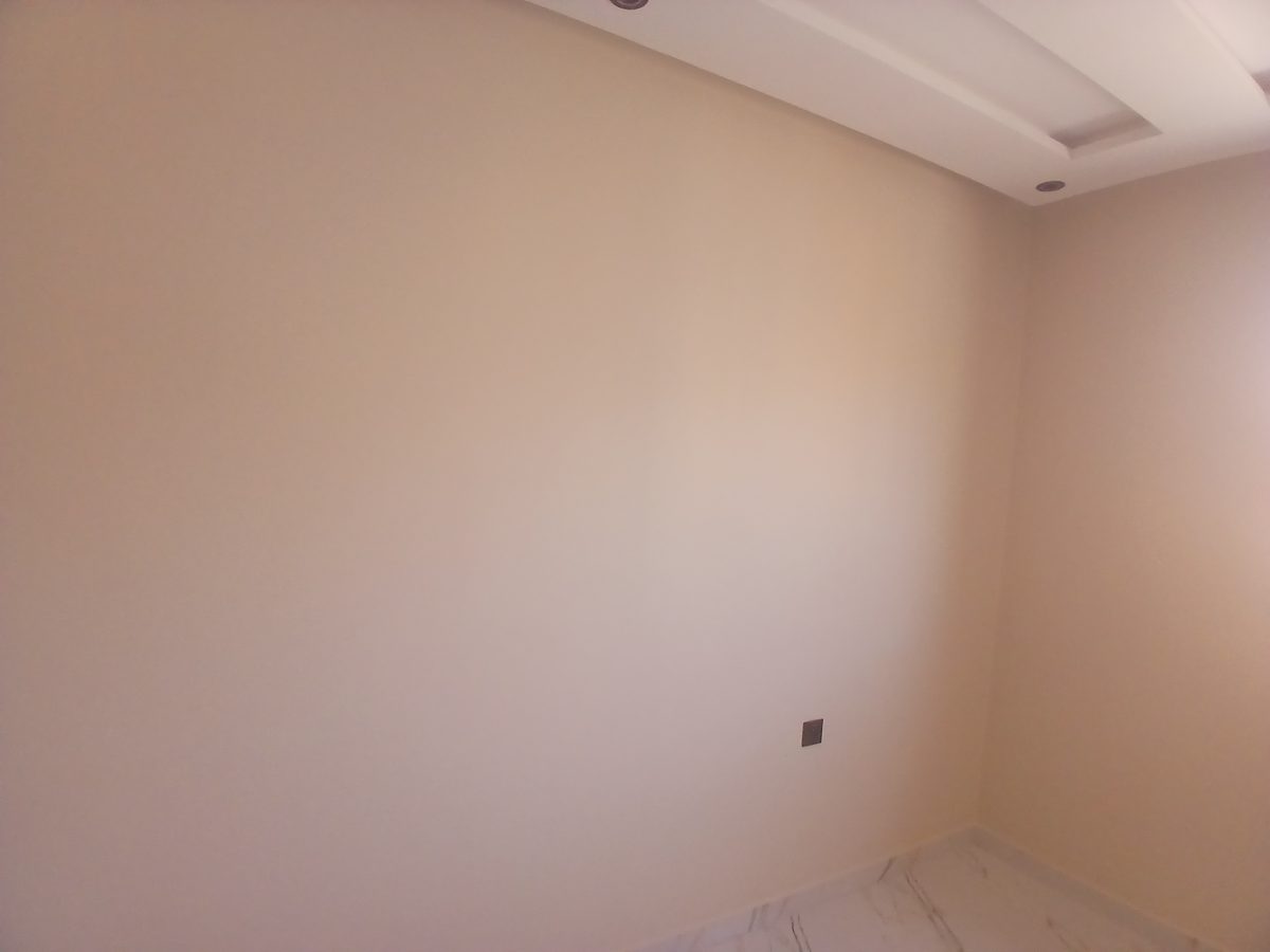 Pièce aux murs peints beige rosé avec faux plafond et sol effet marbre