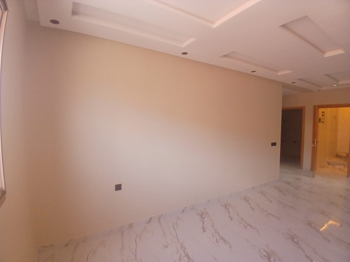 Séjour aux murs peints beige-taupe et faux plafond à caissons