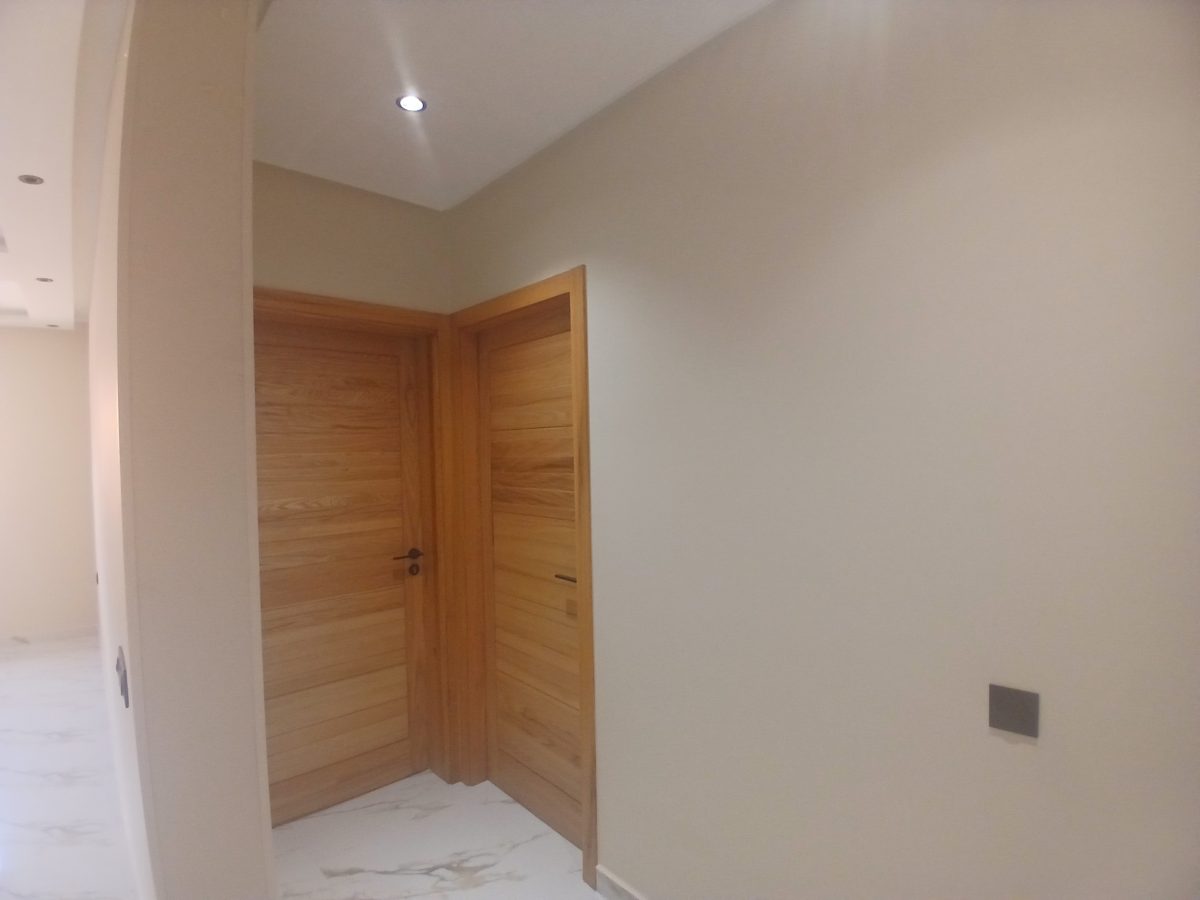 Hall à deux portes en frêne clair et faux plafond courbe à spots