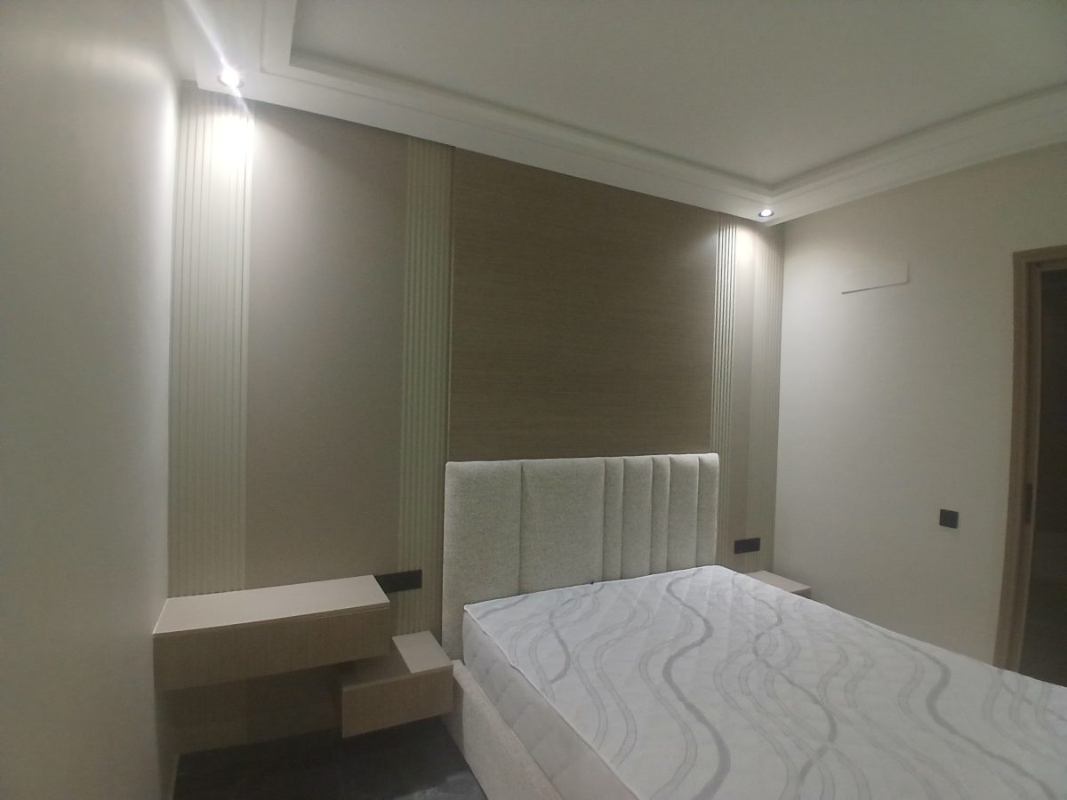 Chambre à tête de lit capitonnée et habillage mural en tasseaux