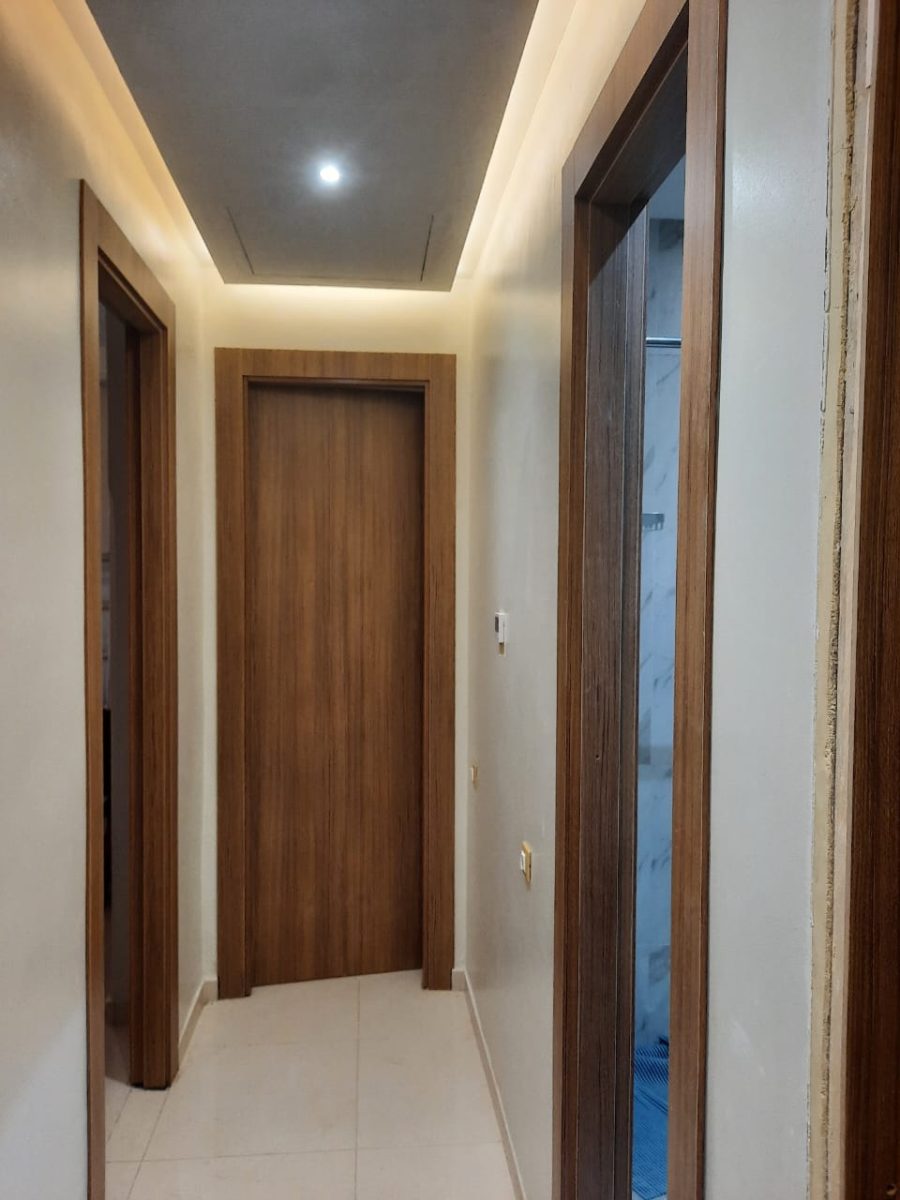 Couloir à portes en bois de noyer et faux plafond à gorge LED