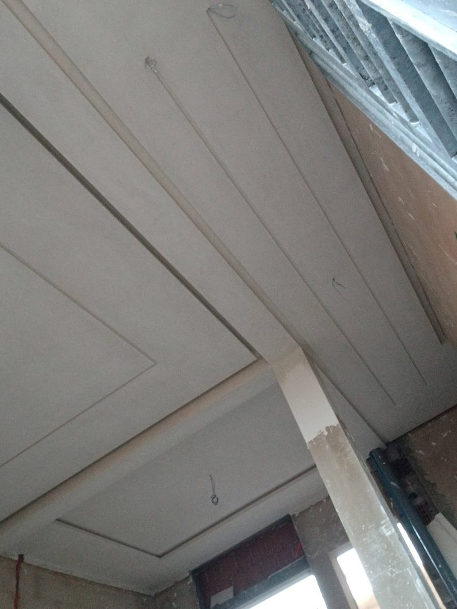 Faux plafond en plâtre à décrochés et moulures parallèles, en cours