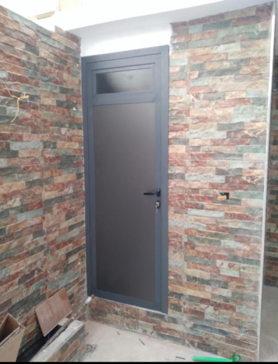 Porte en aluminium anthracite à vitrage dépoli sur parement pierre