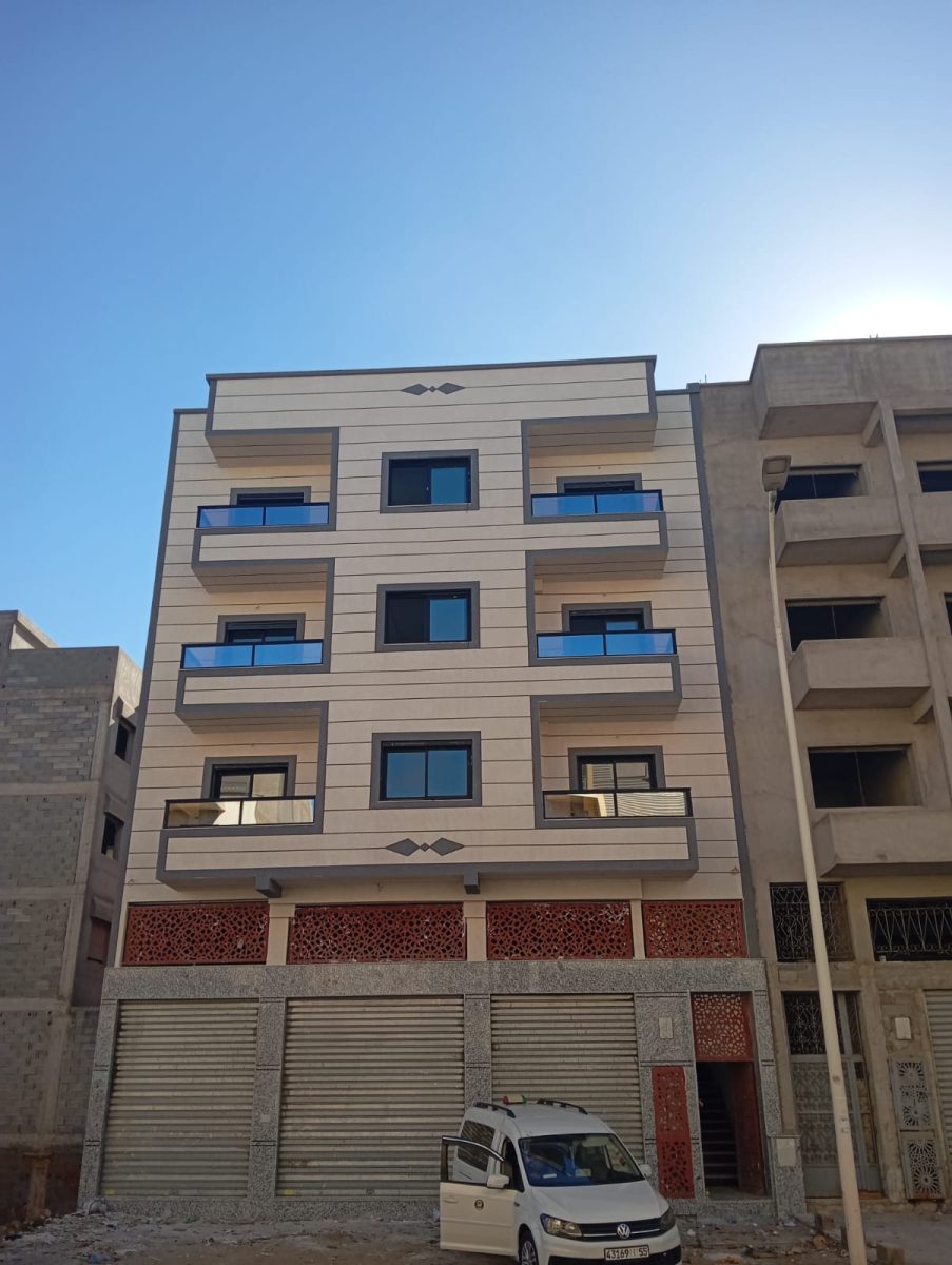 Façade d'immeuble en cladding beige et claustras rouges avec menuiseries alu
