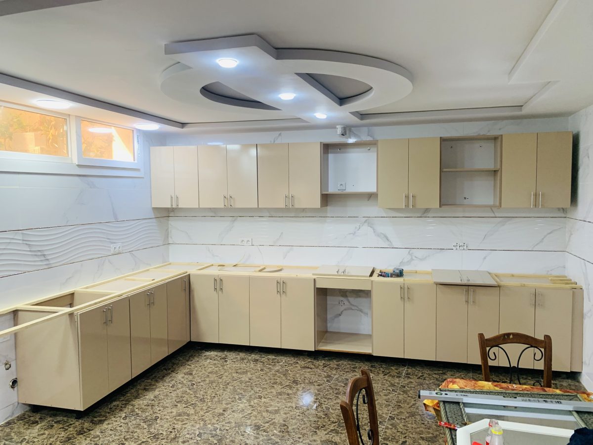 Cuisine en U à caissons crème sous faux plafond LED, en cours